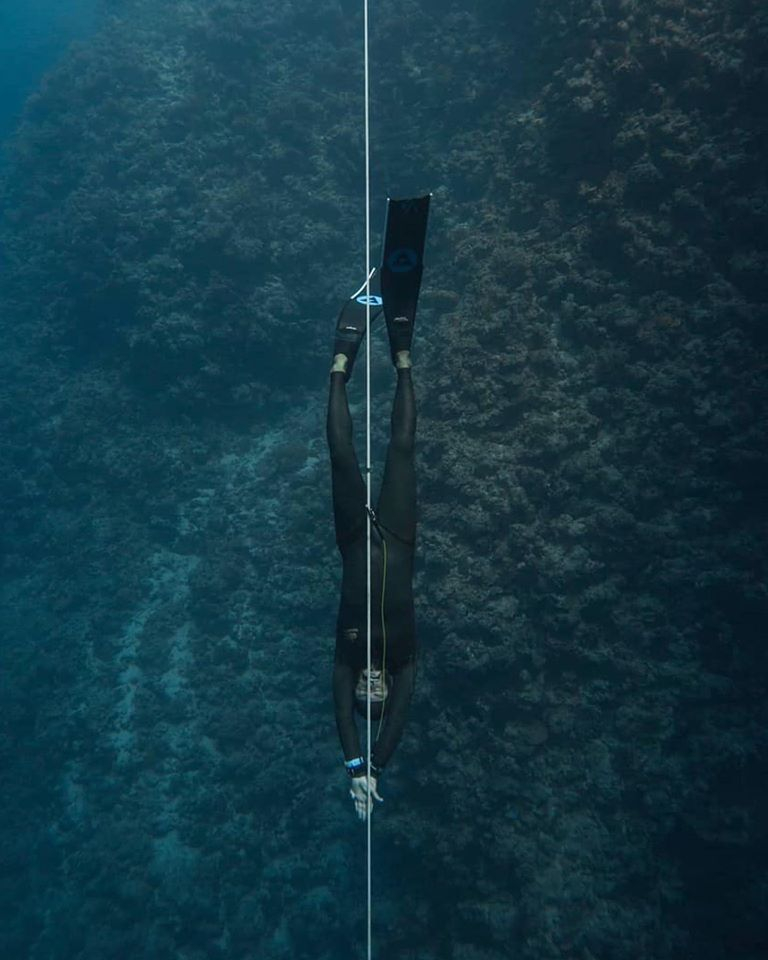 freediver in black wetsuit and alchemy v3 carbon fins underwater