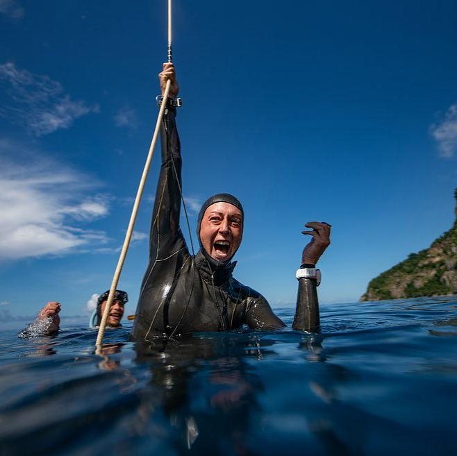 freediver in black wetsuit at sea holding a rope