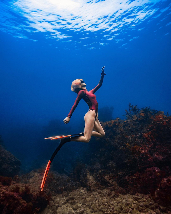 asian woman freediving wearing orange alchemy v330 carbon fins