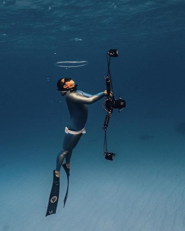 freediver holding a camera and wearing alchemy v3 carbon fins