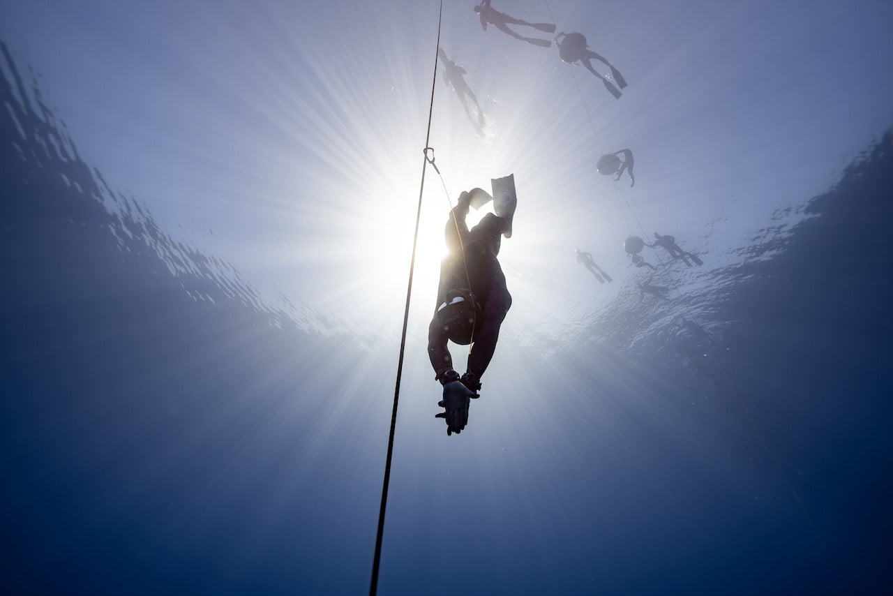 man in wetsuit descending at sea