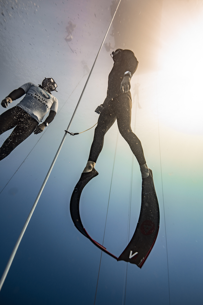 two men freediving at sea under a platform wearing alchemy v3 carbon fins